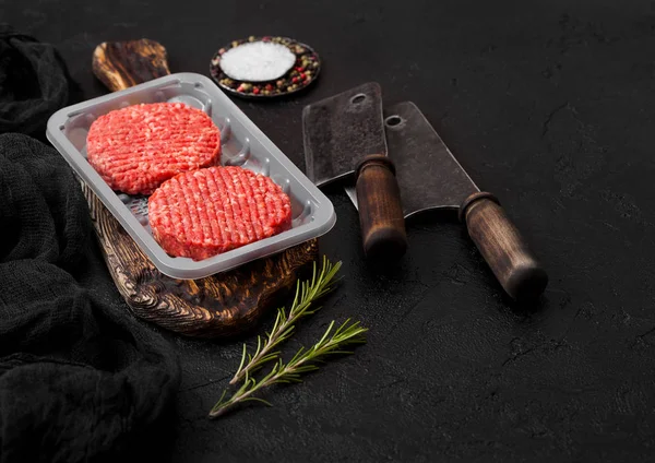 Plateau en plastique avec crus hachés fermiers maison griller burgers de bœuf avec des épices et des herbes et des hachettes de viande sur noir . — Photo