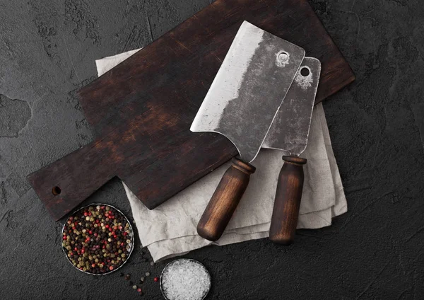 复古肉刀斧头在复古切菜板和黑色石桌背景。屠夫用具。盐和胡椒. — 图库照片