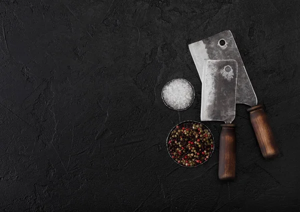 Vintage Fleischmesserbeile auf schwarzem Steintischhintergrund mit Salz und Pfeffer. Metzgerutensilien. Raum für Ihren Text — Stockfoto