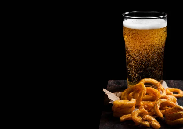 Glas lagger bier met gekrulde frietjes snack op Vintage houten plank op zwarte achtergrond. Ruimte voor tekst — Stockfoto