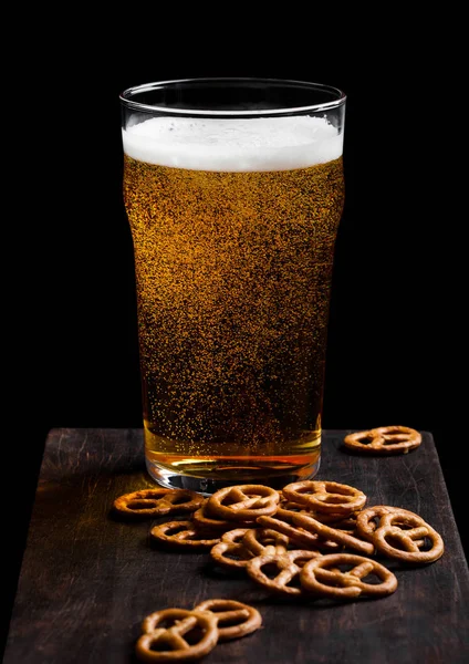 Glas pils bier met zout snack op Vintage houten plank op zwarte achtergrond. Bier en snack — Stockfoto