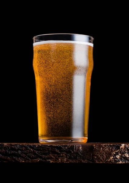 Pohár lager sör, hab és buborékok vintage fából készült táblán a fekete háttér. — Stock Fotó