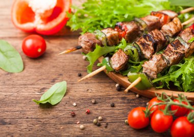 Domates ve biber biberli ahşap arka planda, marul salatası yuvarlak ahşap plaka içinde Paprika ile ızgara domuz ve tavuk kebap.