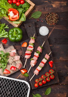 Ahşap arka planda taze sebzeler ve tek kullanımlık Kömür ızgarası ile doğrama tahtasında Paprika ile ham domuz kebap. Tuz ve biber, marul ve biber. Üst görünüm