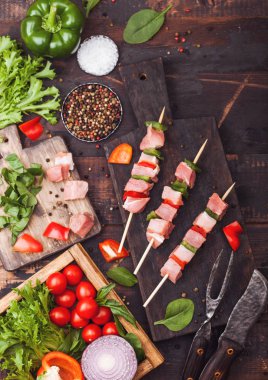 Çatal ve bıçak ile ahşap arka planda taze sebzeler ile doğrama tahtasında Paprika ile ham domuz kebap. Tuz ve biber ile marul ve Paprika ve kiraz domates. Üst görünüm