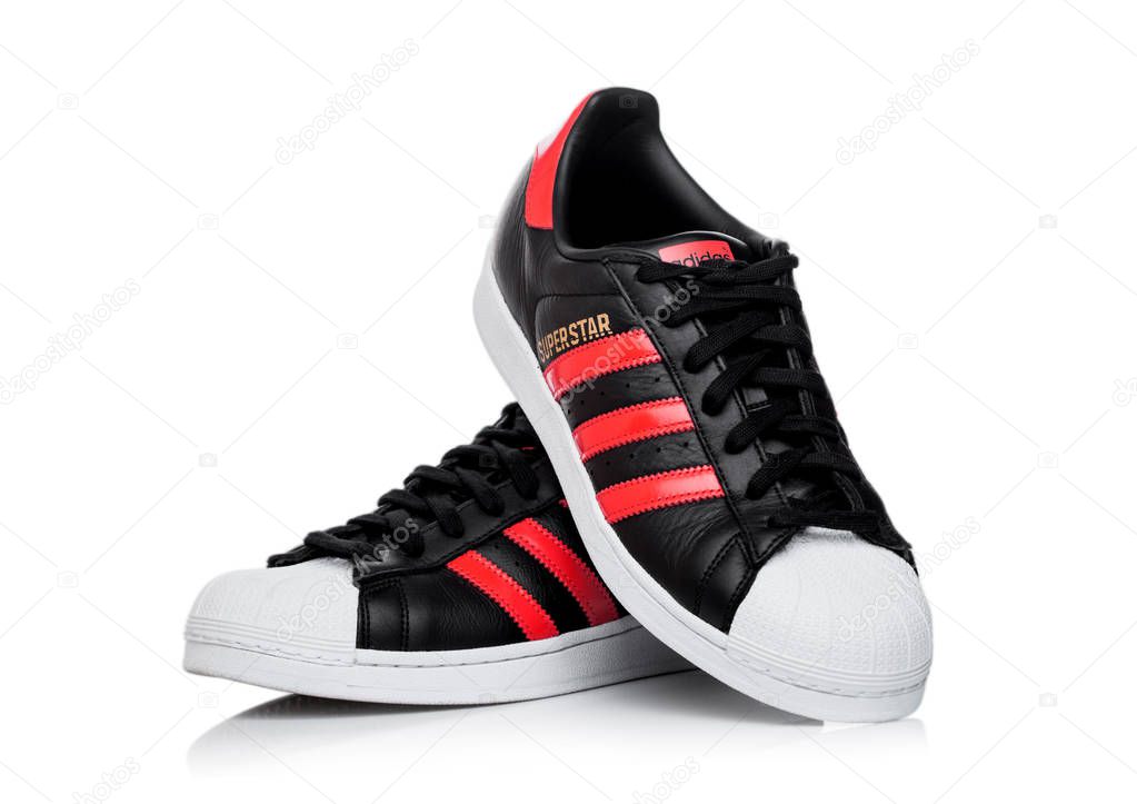 LONDON, UK - JUNE 05, 2019: Adidas Originals Superstar black shoes with red stripes on white background.