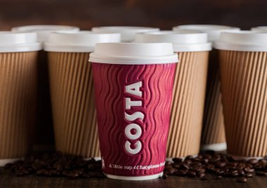 Londra, İngiltere - 05 Haziran 2019: Costa Paper Cup boş kahverengi kahve fincanları ile ahşap arka plan üzerinde kahve çekirdekleri götürmek için.