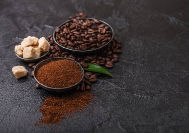 Zemin tozu ve siyah arka plan üzerinde kahve trea yaprağı ile şeker kamışı küpleri ile taze çiğ organik kahve çekirdekleri.