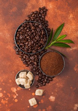 Açık kahverengi arka plan üzerinde kahve trea yaprağı ile zemin tozu ve şeker kamışı küpleri ile taze çiğ organik kahve çekirdekleri.