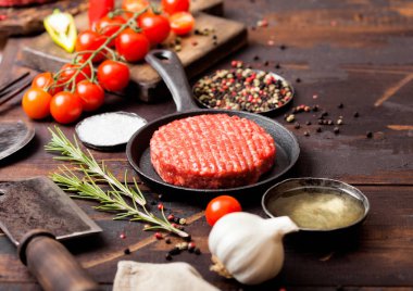 Taze ham kıyılmış ev yapımı çiftçiler ızgara sığır Burger baharat ve otlar ve ahşap tahta üzerinde et balta ile tava. Yağ, sarımsak ve domates.