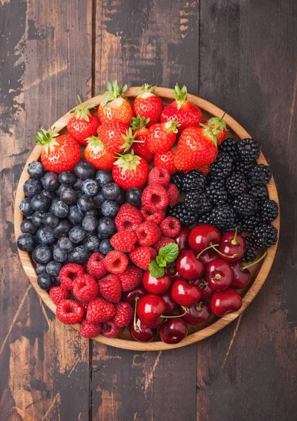 Fresh organic summer berries mix in round wooden tray on light wooden table background. Raspberries, strawberries, blueberries, blackberries. — Stock Photo, Image