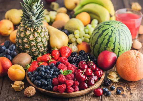 新鲜的有机夏季浆果混合在木托盘和木背景异国情调的水果。树莓，草莓，蓝莓，黑莓和樱桃。西瓜、梨、菠萝、葡萄. — 图库照片