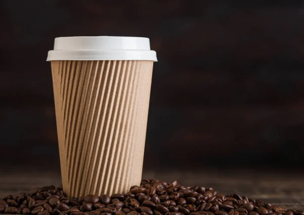 Brown Blank Coffee Paper Cup para llevar con granos de café sobre fondo de madera . — Foto de Stock