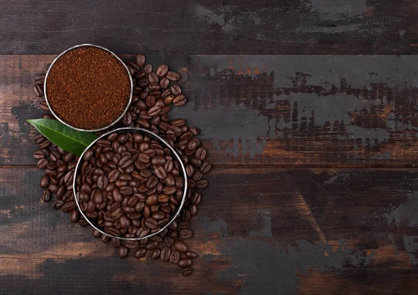 Fresh raw organic coffee beans with ground powder and coffee tree leaf on wooden background. — Stock Photo, Image