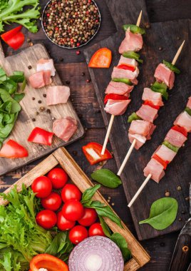 Ahşap arka plan üzerinde taze sebze ile doğrama tahtası üzerinde kırmızı biber ile çiğ domuz kebap. Tuz ve biber marul ve kırmızı biber ve kiraz domates ile. Metin için alan