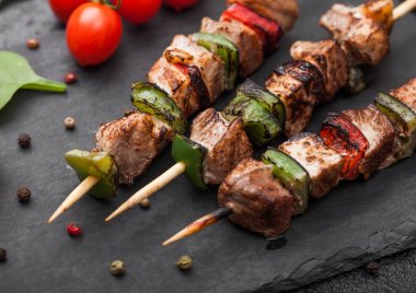 Siyah arka planda tuz, biber ve domates ile taş doğrama tahtasında Paprika ile ızgara domuz eti ve Tavuk Kebabı.