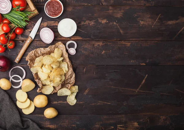 Patatas fritas frescas orgánicas hechas en casa en un tazón de madera con crema agria y cebollas rojas y especias sobre fondo de mesa de madera. Vista superior.Papas amarillas frescas con salsa de tomate — Foto de Stock