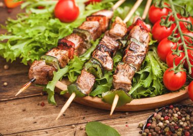 Domates ve ıspanak ile ahşap arka planda, marul salatası yuvarlak ahşap plaka içinde Paprika ile ızgara domuz ve tavuk kebap. Makro