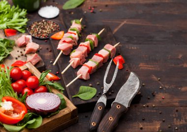 Çatal ve bıçak ile ahşap arka planda taze sebzeler ile doğrama tahtasında Paprika ile ham domuz kebap. Tuz ve biber ile marul ve Paprika ve kiraz domates. Metin alanı