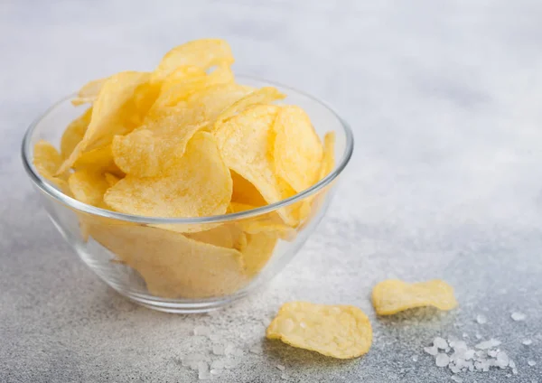 Prato tigela de vidro com batatas fritas batatas fritas com sabor de cebola com sal sobre fundo mesa de luz . — Fotografia de Stock