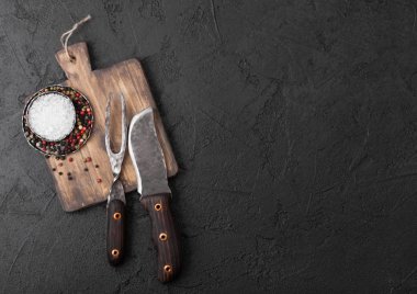 Vintage et bıçak ve çatal vintage doğrama tahtası ve siyah taş tablo arka planı. Kasap kaplar. Tuz ve biber.