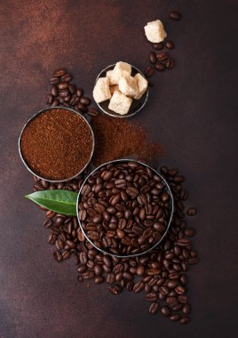 Taze çiğ organik kahve çekirdekleri zemin tozu ve kahverengi arka plan üzerinde kahve trea yaprağı ile şeker kamışı küpleri.