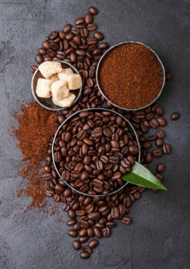 Zemin tozu ve siyah arka plan üzerinde kahve trea yaprağı ile şeker kamışı küpleri ile taze çiğ organik kahve çekirdekleri.