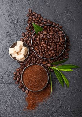 Zemin tozu ve siyah arka plan üzerinde kahve trea yaprağı ile şeker kamışı küpleri ile taze çiğ organik kahve çekirdekleri.