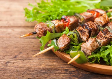 Ahşap arka planda marul salata yuvarlak ahşap plaka içinde Paprika ile ızgara domuz ve tavuk kebap.