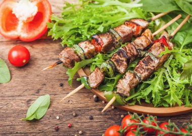 Domates ve biber ve ıspanak ile ahşap arka planda, marul salatası yuvarlak ahşap plaka içinde Paprika ile ızgara domuz ve tavuk kebap.