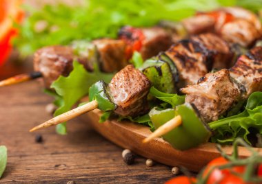 Domates ve biber ve ıspanak ile ahşap arka planda, marul salatası yuvarlak ahşap plaka içinde Paprika ile ızgara domuz ve tavuk kebap.