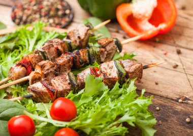 Domates ve biber ve ıspanak ile ahşap arka planda, marul salatası yuvarlak ahşap plaka içinde Paprika ile ızgara domuz ve tavuk kebap.