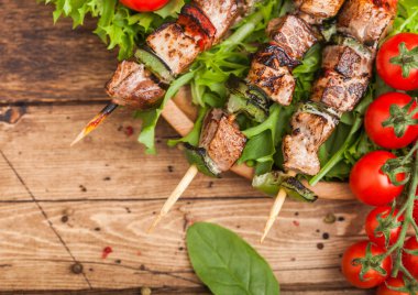 Domates ve ıspanak ile ahşap arka planda, marul salatası yuvarlak ahşap plaka içinde Paprika ile ızgara domuz ve tavuk kebap. Üst görünüm