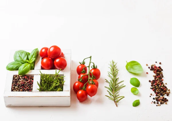 Tomates cereja orgânicos com manjericão e pimenta e alecrim em caixa de madeira branca no fundo da cozinha de pedra. Conceito de cozinha — Fotografia de Stock