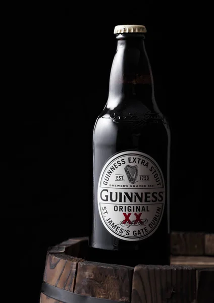 Londen, VK-27 april 2018: fles Guinness origineel stout bier bovenop oude houten vat. — Stockfoto