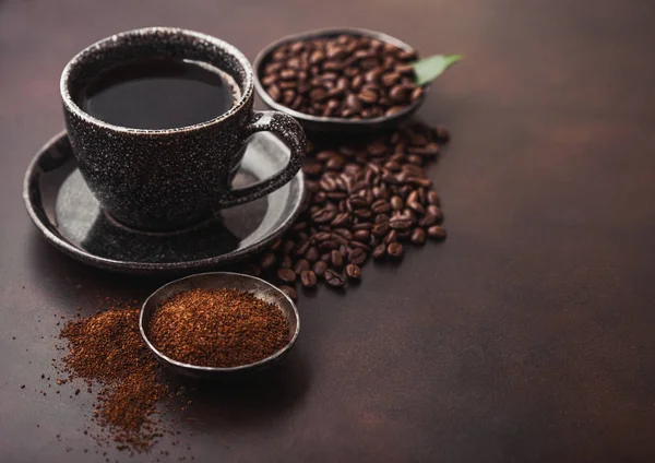 Kahverengi arka plan üzerinde kahve ağacı yaprağı ile şeker kamışı küpleri ile fasulye ve zemin tozu ile taze ham organik kahve Fincan.