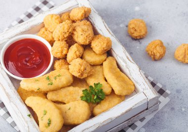Hafif arka planda ketçap ile beyaz vintage ahşap kutu tereyağlı tavuk nuggets ve patlamış mısır ısırıkları. Üstte görüntü. 