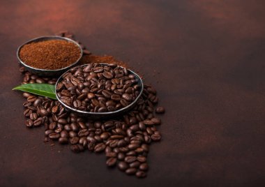 Taze çiğ organik kahve çekirdekleri zemin tozu ve kahve trea yaprağı kahverengi arka plan üzerinde.