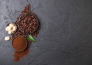 Zemin tozu ve siyah arka plan üzerinde kahve trea yaprağı ile şeker kamışı küpleri ile taze çiğ organik kahve çekirdekleri.