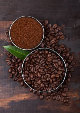 Ahşap arka plan üzerinde zemin tozu ve kahve ağacı yaprağı ile taze çiğ organik kahve çekirdekleri.