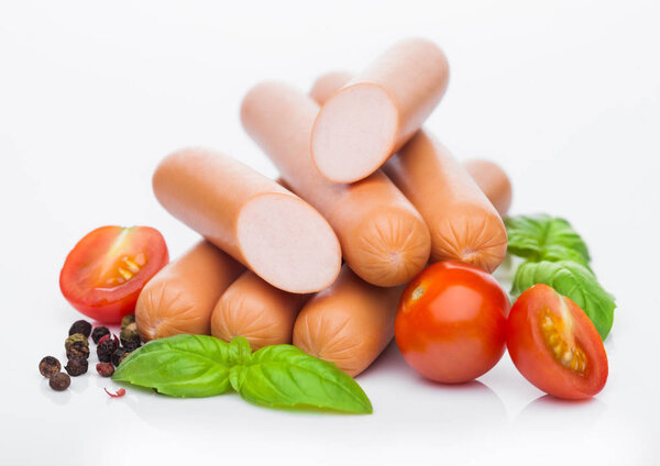 Классические колбасы из свинины с перцем и базиликом и помидорами черри на белом фоне
. 