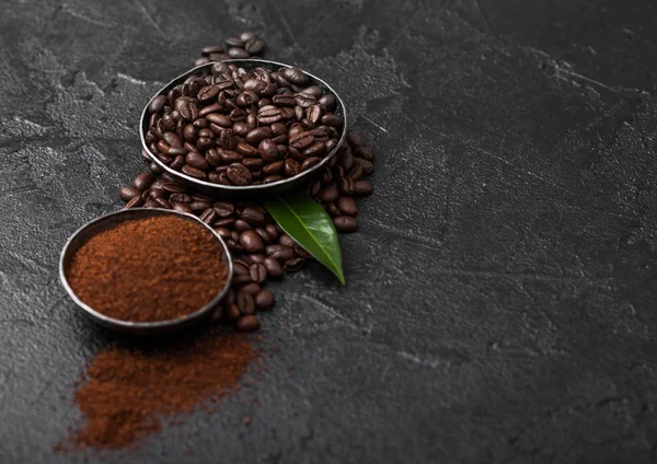 Siyah arka plan üzerinde zemin tozu ve kahve trea yaprağı ile taze çiğ organik kahve çekirdekleri.