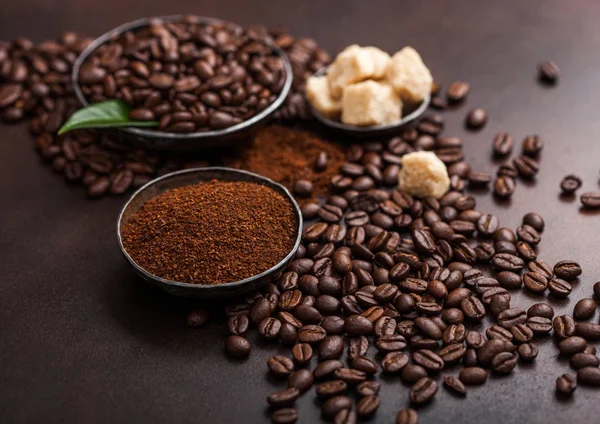 Φρέσκους σπόρους νωπού βιολογικού καφέ με αλεσμένο σκόνη και κύβους ζάχαρης από ζαχαροκάλαμο με φύλλο καφέ σε καφέ φόντο. — Φωτογραφία Αρχείου