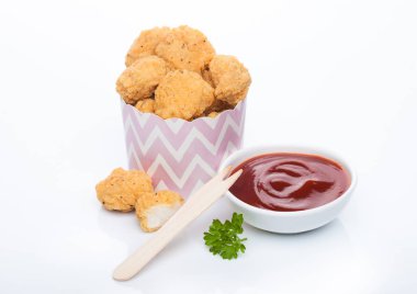Tahta çatal ve ketçapla beyaz arka planda fast food yemek için çocuk bardağında çıtır çıtır tavuk patlağı ısırıkları..