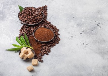 Hafif mutfak masa arka plan üzerinde kahve trea yaprağı ile zemin tozu ve şeker kamışı küpleri ile taze çiğ organik kahve çekirdekleri.