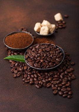 Taze çiğ organik kahve çekirdekleri zemin tozu ve kahverengi arka plan üzerinde kahve trea yaprağı ile şeker kamışı küpleri.