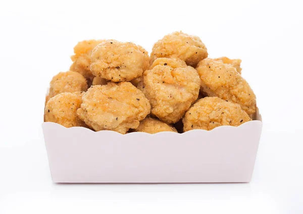Τραγανό κοτόπουλο ποπ κορν δαγκώματα σε παιδικό χάρτινο τετράγωνο κύπελλο για fast food γεύματα σε λευκό φόντο. — Φωτογραφία Αρχείου