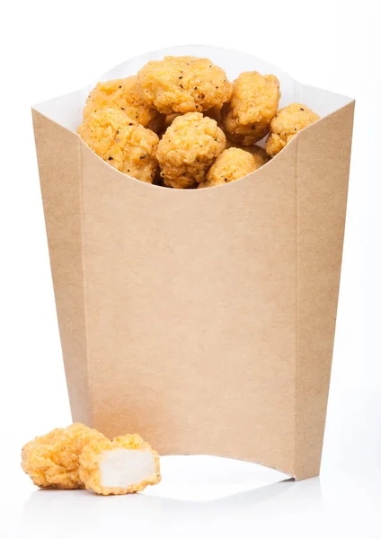 Τραγανό κοτόπουλο ποπ κορν δαγκώματα σε χάρτινο δοχείο για fast food γεύματα σε λευκό φόντο. — Φωτογραφία Αρχείου