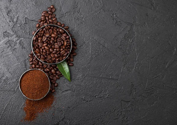 Fresh raw organic coffee beans with ground powder and coffee trea leaf on black background. — Stock Photo, Image
