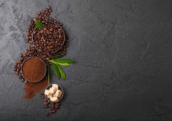 Świeże Surowe organiczne ziarna kawy z mielonej proszku i kostki cukru trzcinowego z liści kawy TREA na czarnym tle. — Zdjęcie stockowe